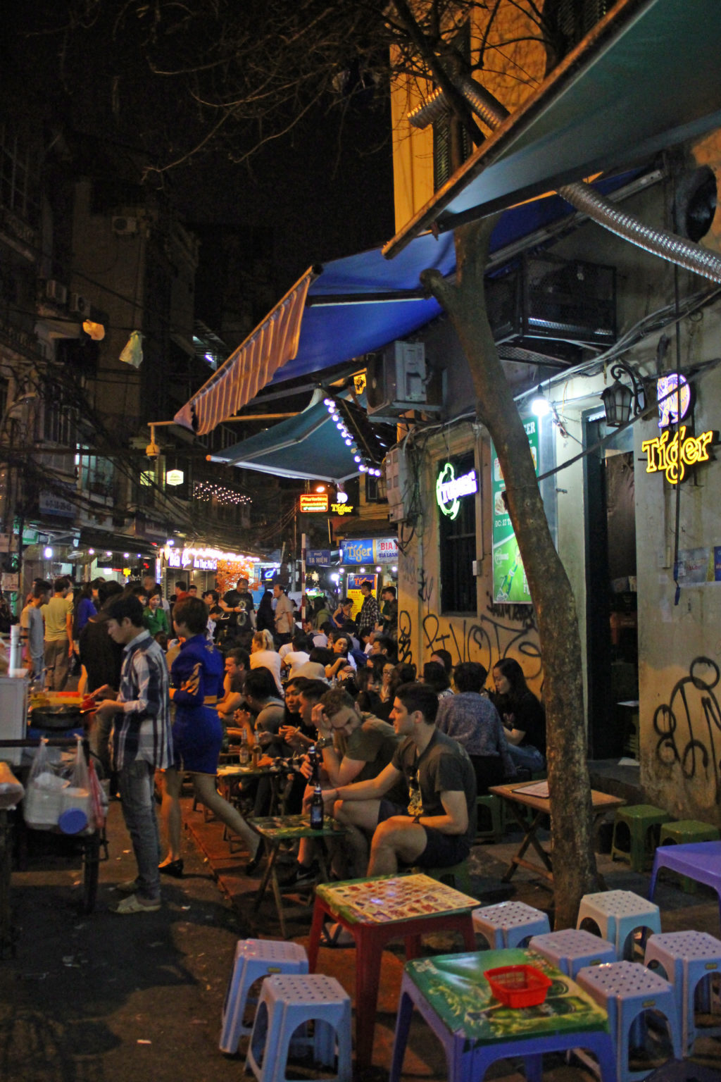 Tische vor einem Streetfoodladen in Hanois Altstadt nachts