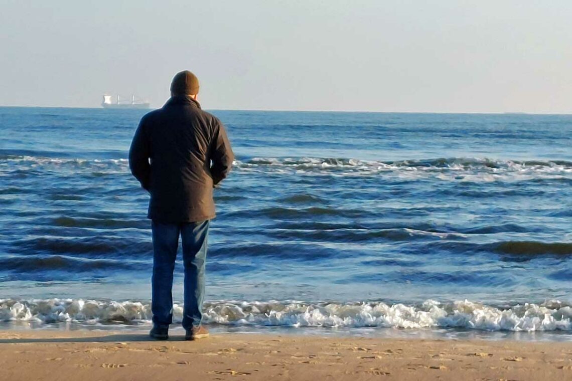 Mann von hinten blickt aufs Meer